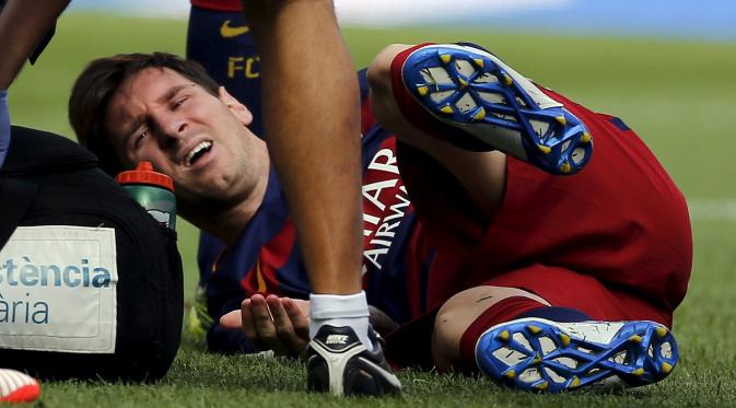 Barcelona's Lionel Messi grimaces as he lies on the pitch after injuring his left knee during their Spanish first division soccer match against Las Palmas at Camp Nou stadium in Barcelona, Spain, September 26, 2015. REUTERS/Sergio Perez