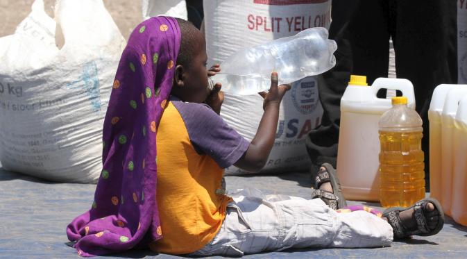 Seorang anak minum air di dekat jatah bantuan makanan dari World Food Programme di Chiredzi Mupinga, Zimbabwe, Selasa (6/10). Puluhan juta orang di sub-Sahara Afrika terancam kelaparan akibat siklus El Nino mencapai puncaknya.(REUTERS/Philimon Bulawayo)