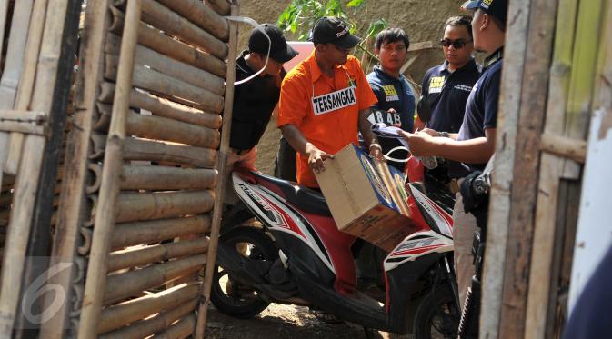 Tersangka Agus Dermawan saat bersiap mengendarai motor untuk membawa mayat korban di dalam kardus, Jakarta, Selasa (20/10/2015). Proses rekonstruksi pembunuhan bocah dalam kardus  menjadi tontonan warga sekitar. (Liputan6.com/Gempur M Surya)