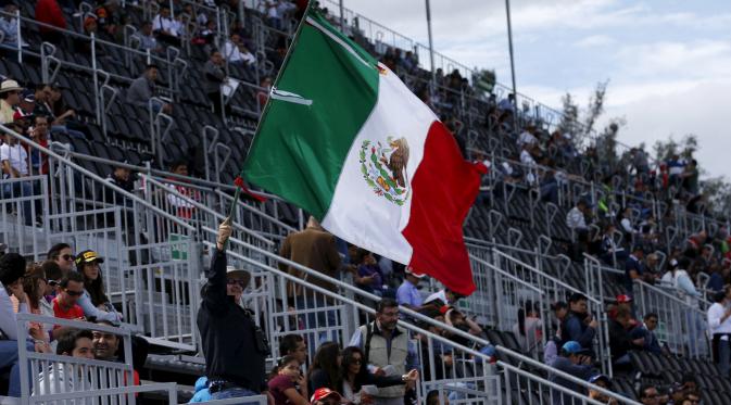 Seorang penonton mengibarkan bendera Meksiko selama sesi latihan berlangsung di Autodromo Hermanos Rodriguez, Meksiko, (30/10/2015). Meksiko akan kembali menggelar kejuaraan dunia Formula One setelah absen sejak 1992. (REUTERS/Henry Romero)