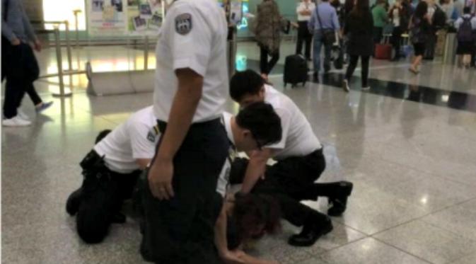 Seorang wanita menyerang para petugas bandara setelah bersitegang selagi dilakukan pemeriksaankeamanan terhadapnya. (Sumber Chinanews via Shanghaiist.com)