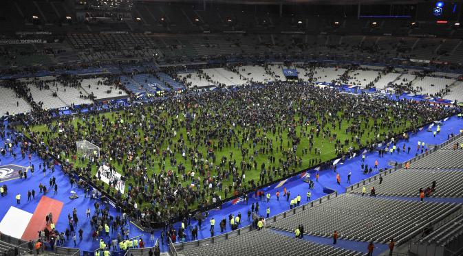 Ribuan Penonton berhamburan di lapangan stadion Stade de France saat menyaksikan pertandingan persahabatan antara Prancis melawan Jerman di Saint-Denis, Paris, (13/11). Serangan bom terjadi di dekat stadion Stade de France Prancis. (AFP PHOTO/FRANCK FIFE)