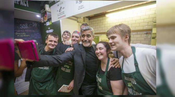 George Clooney sempatkan diri untuk melakukan 'selfie' dengan karyawan toko di Edinburgh. (NY Daily News)