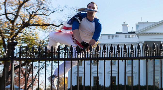 Seorang pria berselimut bendera Amerika Serikat tampak melompati pagar Gedung Putih di Washington, Kamis (26/11). Insiden itu terjadi pada saat Presiden AS Barack Obama sedang berada di dalam Gedung Putih merayakan hari Thanksgiving. (dailymail.co.uk)