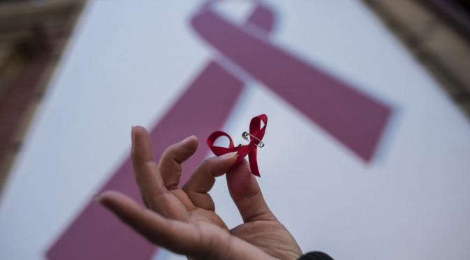 Perempuan memegang simbol pita ketika demo di Hari AIDS Sedunia, Pamplona, Spanyol, Senin (1/12). | via: Alvaro Barrientos/AP Photo
