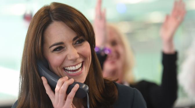 Duchess of Cambridge, Kate Middleton tertawa sambil menggenggam gagang telepon saat menjadi broker dalam acara amal tahunan ICAP di London, Inggris, Rabu (9/12/2015). (AFP PHOTO/POOL/JEREMY Selwyn)
