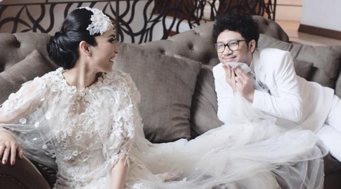 Nampak Kunto Aji dan istri duduk di sebuah sofa dan memakai busana pengantin modern bernuansa putih. Sisi humoris Kunto Aji terlihat disini, ia justru menarik gaun sang istri dan menutupi sebagian wajahnya. (via instagram/@uchiet)