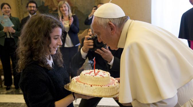 Paus Fransiskus meniup lilin kue ulang tahunnya yang diberikan oleh seorang anggota Italian Catholic Action saat ulang tahun ke-79 tahun di Vatikan, Kamis (17/12/2015). (REUTERS/Osservatore Romano)