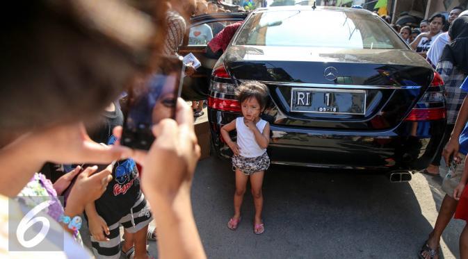 Seorang anak berpose di belakang mobil yang digunakan Presiden Joko Widodo dan Ibu Negara saat blusukan ke Kedoya dan Petamburan, Jakarta, Selasa (1/9/2015). (Liputan6.com/Faizal Fanani)