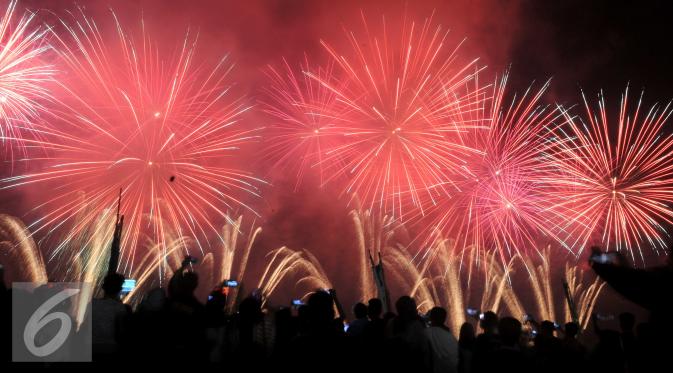 Sejumlah warga melihat pertunjukan pesta kembang api  yang menghiasi langit di kawasan wisata Ancol, Jakarta, Jumat (1/1/2015). Pergantian malam tahun 2015 diwarnai kembang api yang sangat spektakuler di kawasan tersebut. (Liputan6.com/Gempur M Surya)