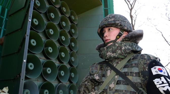 Tentara Korsel berdiri di dekat pengeras suara yang dipasang di sebelah selatan zona demiliterisasi, Yeoncheon, Jumat (8/1/2016). Pengeras suara tersebut memasang musik pop Korea, berita dan kritik atas Korea Utara ke arah perbatasan. (YONHAP/AFP)