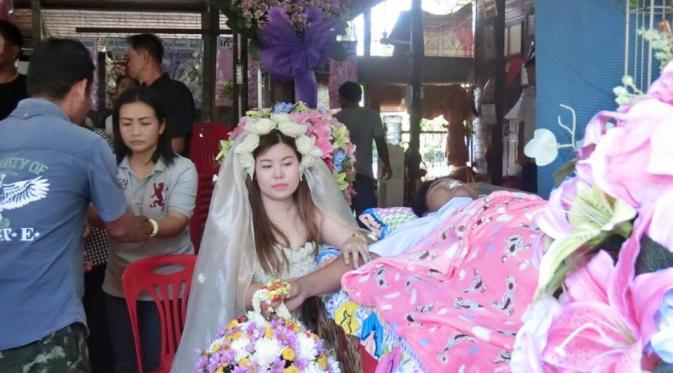 Ia menggunakan gaun pengantin lengkap dengan hiasan kepala. (Via: facebook.com/akiyawong)
