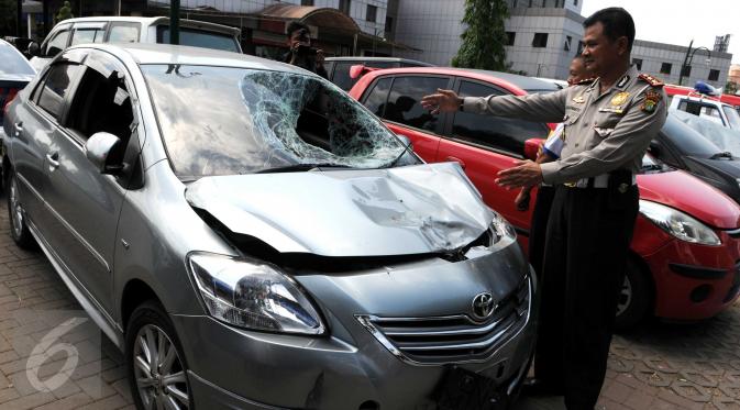 Petugas kepolisian menunjukkan mobil yang menabrak pejalan kaki di Jalan Boulevard Artha Gading, Jakarta, Sabtu (9/1/2016). Akibat kejadian tersebut, satu pengendara sepeda dan satu pejalan kaki meninggal di lokasi. (Liputan6.com/Helmi Afandi)