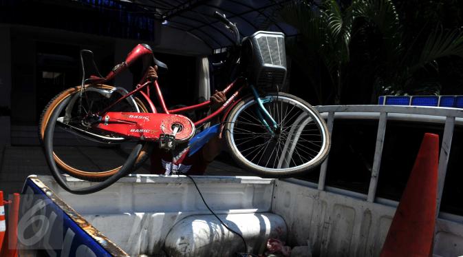 Petugas kepolisian mengangkat sepeda yang ditabrak mobil di Jalan Boulevard Artha Gading, Jakarta, Sabtu (9/1/2016). Akibat kejadian tersebut, satu pengendara sepeda dan satu pejalan kaki meninggal di lokasi. (Liputan6.com/Helmi Afandi)