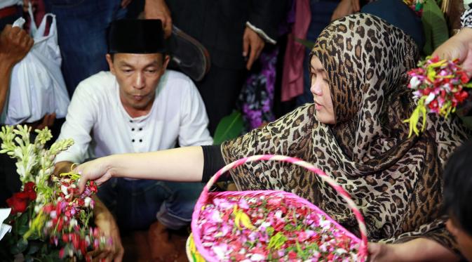 Istri Alm. Budi Anduk menaburkan bunga di pusara sang suami. (Deki Prayoga/bintang.com)