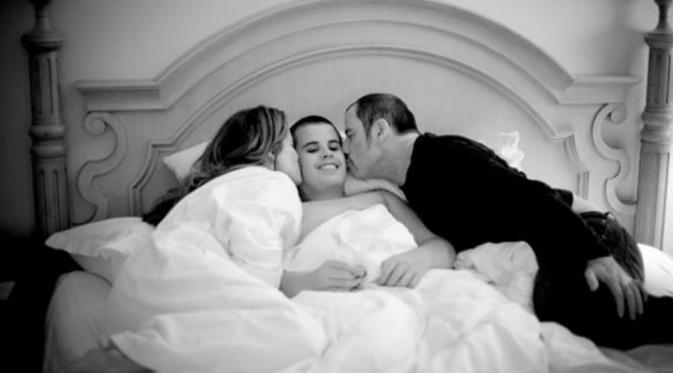 John Travolta dan istri, Kelly Preston tengah mencium Jett Travolta [foto: Closer Weekly]