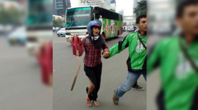 Seorang Gojek driver tampak menyelamatkan seorang perempuan dengan kaki terluka dari lokasi kejadian Sarinah