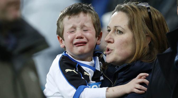 Anak seorang fans menangis saat menyaksikan laga antara Newcastle melawan Manchester United pada lanjutan Liga Premier di ST James Park, Inggris, Selasa (12/1/2016). Kedua tim bermain imbang. (Reuters/Andrew Yates)