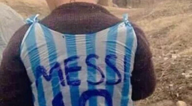Pesepakbola Lionel Messi tengah 'memburu' bocah yang mengenakan 'jersey' kresek biru-putih bernomor 10 ini. Siapa ya dia?