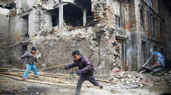 Anak-anak bermain di dekat bangunan yang rusak akibat gempa tahun lalu di Nepal, Jum'at (29/1/2016). Gempa bumi pada bulan April dan Mei 2015 silam menewaskan hampir 9.000 orang dalam bencana alam terburuk Nepal. (Reuters/Navesh Chitrakar)