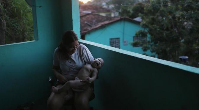 Seorang wanita di Recife, Brasil, menggendong bayi yang sakit dengan infeksi virus Zika. (Via: news.nationalgeographic.com)