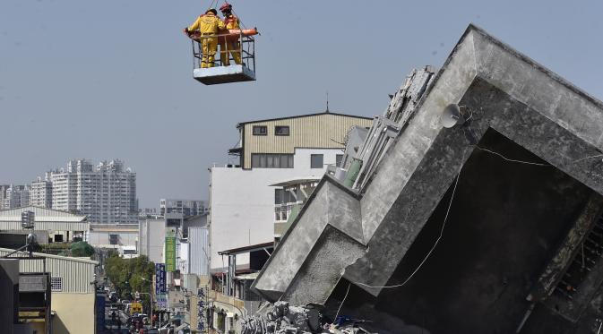 Lee Tsung-tien (42) diangkat dengan menggunakan crane oleh regu penyelamat di apartemen yang ambruk akibat gempa di kota Tainan, Taiwan, Senin (8/2). Dua korban berhasil diselamatkan setelah terperangkap selama lebih dari 50 jam. (AFP PHOTO/Sam Yeh)