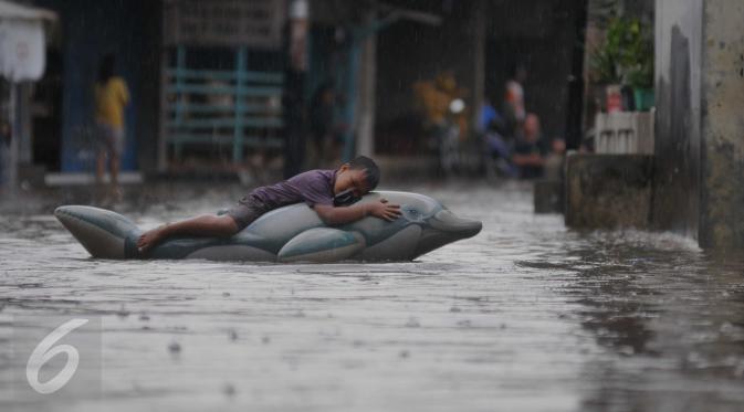 Seorang anak bermain saat banjir menggenangi kawasan Pasar Buncit, Jakarta Selatan, Selasa (9/2/2016). Banjir menggenangi kawasan tersebut hingga setinggi 100 cm akibat luapan Kali Kemang. (Liputan6.com/Gempur M Surya)