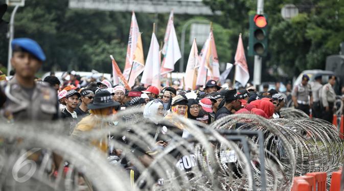 Massa berdiri di depan barikade kawat berduri yang dipasang di seputaran Istana Kepresidenan, Jakarta, Rabu (10/2). Guru honorer dari seluruh Indonesia itu menuntut Pemerintah agar mengangkat mereka sebagai PNS. (Liputan6.com/Faizal Fanani)