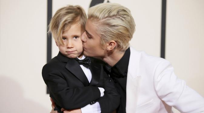 Justin Bieber mencium adiknya, Jaxon, saat berpose di karpet merah Grammy Awards 2016 di Staples Center, Los Angeles, Senin (15/2). Meski terpaut usia 15 tahun, namun pelantun 'What Do You Mean' itu tampak dekat dengan sang adik. (REUTERS/Danny Moloshok)