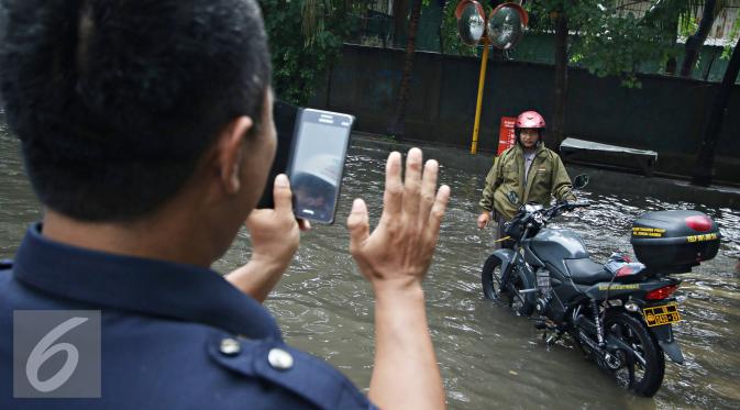 Warga berpose disamping motor saat banjir menggenangi kawasan Sunter, Jakarta, Kamis (25/2). Hujan deras yang mengguyur Jakarta serta sistem drainase yang buruk menjadi penyebab banjir sehingga mengganggu aktivitas warga. (Liputan6.com/Immanuel Antonius)