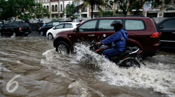 Pengendara motor saat menerobos genangan air di kawasan Kelapa Gading, Jakarta, Jumat (26/2/2016). Hujan deras yang mengguyur Ibukota membuat beberapa ruas jalanan tersendat. (Liputan6.com/Faizal Fanani)