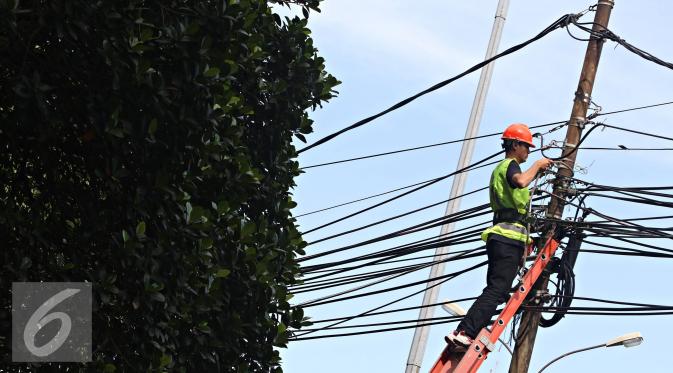 Pekerja mengecek instalasi kabel di tiang listrik milik PLN, Jakarta, Jumat (26/2). PLN menjaga mutu keandalan penyaluran tenaga listrik, memenuhi ketentuan keselamatan ketenagalistrikan, dan estetika tata kota Jakarta. (Liputan6.com/Immanuel Antonius)