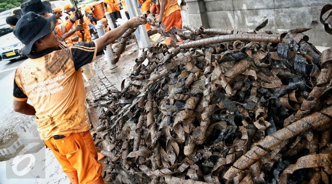 Petugas kebersihan mengumpulkan bungkusan kabel yang menyumbat saluran air di Jalan Merdeka Selatan, Jakarta, Senin (29/2). Basuki Tjahaja Purnama (Ahok) mengatakan adanya dugaan sabotase banjir akibat limbah kulit kabel itu. (Liputan6.com/Faizal Fanani)