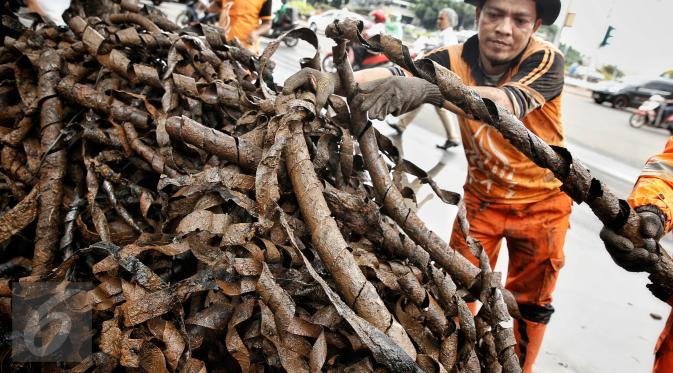 Petugas kebersihan menata bungkusan kabel yang menyumbat saluran air di Jalan Merdeka Selatan, Jakarta, Senin (29/2). Basuki Tjahaja Purnama (Ahok) mengatakan adanya dugaan sabotase banjir akibat limbah kulit kabel itu. (Liputan6.com/Faizal Fanani)