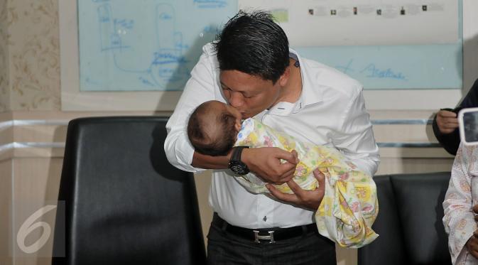 Kombes Krishna Murti mencium bayi saat memberi keterangan pers terkait sindikat penjualan bayi di Polda Metro Jaya, Jakarta, Selasa (1/3/2016). Sebelumnya, Senin (29/1) polisi menangkap 4 pelaku penculikan dan jual beli anak. (Liputan6.com/Johan Tallo)