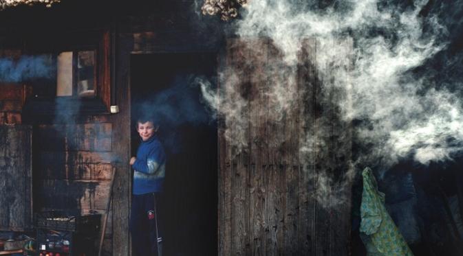 Seorang anak lelaki di depan rumah sederhana. (Alex Robciuc/Barcroft Media)