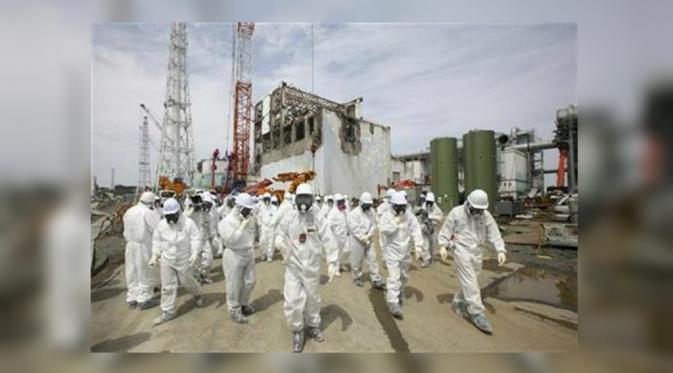 Para awak media dan pekerja TEPCO nampak memakai baju dan masker pelindung di depan pabrik pembangkit listrik tenaga nuklir Fukushima Daiichi (Foto: Reuters).