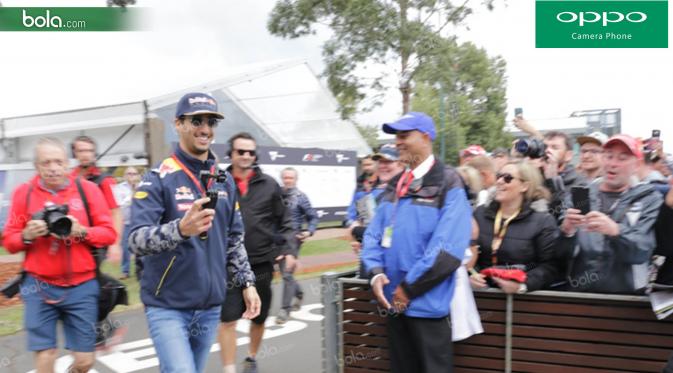 Pebalap Red Bull Racing asal Australia, Daniel Ricciardo, sumringah ketika disambut fans saat melintasi area fan zone jelang GP Australia di Sirkuit Albert Park, Melbourne, Sabtu (19/3/2016). (Bola.com/Yus Mei Sawitri)
