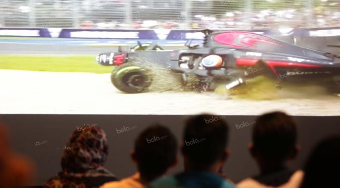 Penggemar Rio Haryanto serius menyaksikan kecelakaan yang menimpa pebalap Fernando Alonso pada balapan Fomula 1 di Resotran Brewerkz, Senayan City, Jakarta, Minggu (20/3/2016). (Bola.com/Nicklas Hanoatubun )
