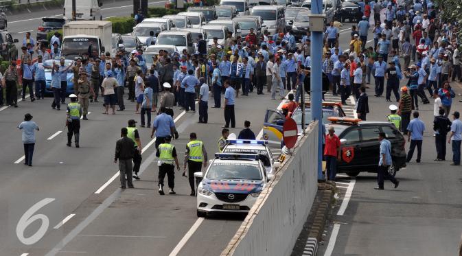 Petugas saat mengatur aksi demo supir taksi di dalam jalan tol Gatot Subroto, Jakarta, Selasa (22/3). Selain melakukan demo supir taxi tersebut melakukan sweeping ke sopir taksi yang beroperasi di dalam tol, dan membakar ban.(Liputan6.com/Johan Tallo)