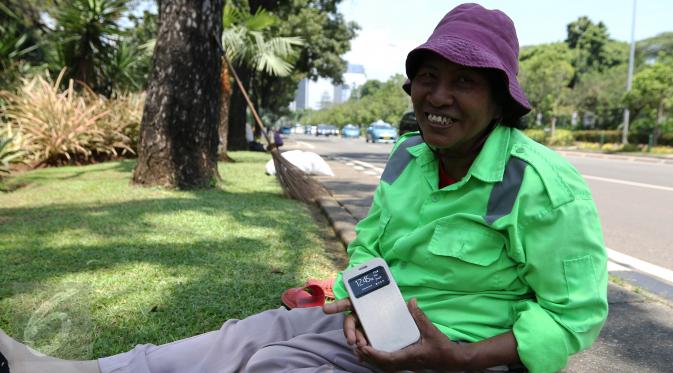 Sambil tersenyum, Ibu Tuti menunjukan ponsel baru miliknya hasil pemberian Gubernur DKI Jakarta, (24/3). Wanita 54 tahun ini mendapatkan hadiah ponsel karena aksinya yang berani memarahi pendemo perusak Balai Kota. (Liputan6.com/Yoppy Renato)