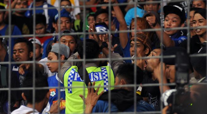 Personil polisi berusaha menenangkan suporter saat laga final Piala Bhayangkara 2016 antara  Arema Cronus vs Persib di Stadion GBK Jakarta, Minggu (3/4/2016). Laga diwarnai aksi protes dari   suporter dan official Persib. (Liputan6.com/Helmi Fithriansyah)