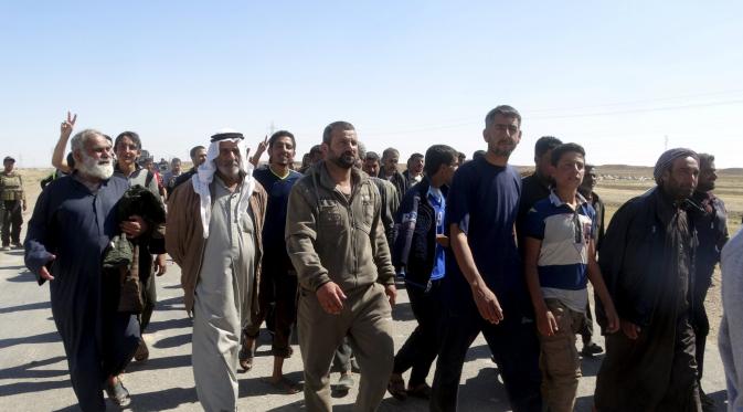Puluhan warga berjalan saat melarikan diri setelah terjadi pertempuran antara pasukan Irak dan militas ISIS di kota Hit, provinsi Anbar, (5/4/2016). (REUTERS/Stringer)