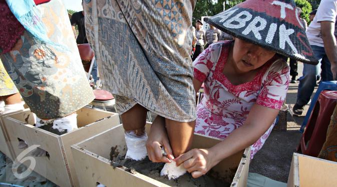 Seorang perempuan membantu temannya menyemen kaki saat aksi di depan Istana Negara, Jakarta, Selasa (12/4). Aksi tersebut merupakan bentuk protes atas pembangunan pabrik semen di wilayah mereka. (Liputan6.com/Immanuel Antonius) 