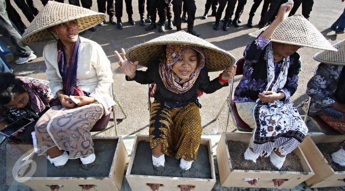 Sejumlah perempuan asal Pegunungan Kendeng, Jawa Tengah melakukan aksi semen kaki di depan Istana Negara, Jakarta, Selasa (12/4). Aksi tersebut merupakan bentuk protes atas pembangunan pabrik semen di wilayah mereka. (Liputan6.com/Immanuel Antonius) 