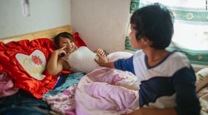 Wen, 18 menyentuh perut Jie (13) yang tengah hamil. (Muyi Xiao/CNN)