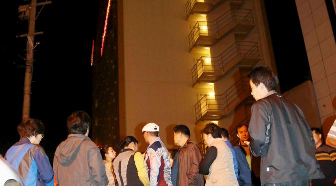 Sejumlah orang berhamburan ke jalan di depan sebuah hotel setelah gempa bumi mennguncang Kumamoto, Jepang selatan, Kamis (14/4). Gempa 6,4 SR itu juga mengakibatkan lebih dari 20 bangunan rumah hancur dan kebakaran di Prefektur Kumamoto. (REUTERS/Kyodo)