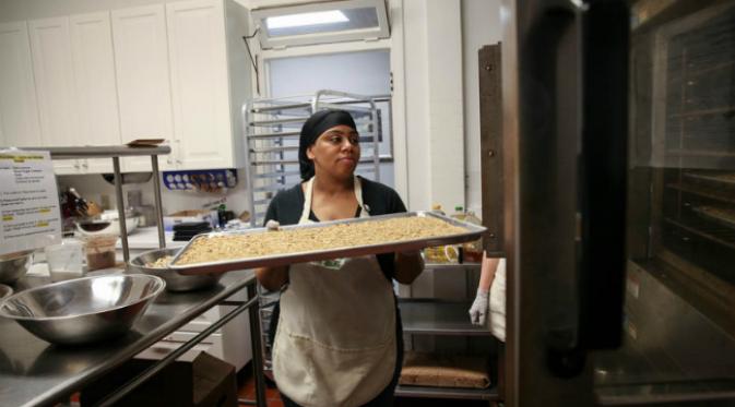 Colida Johnson, lulusan program yang sekarang menjadi asisten program, memasukan granola dalam oven. (Sumber Morgan McCloy/NPR)