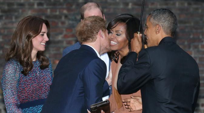 Pangeran Harry saat mencium pipi Michelle Obama saat Presiden AS Barack Obama berkunjung ke Kensington Palace, London , Inggris (22/4). Mereka akan mengadakan acara makan malam. (REUTERS / Kevin Lamarque)