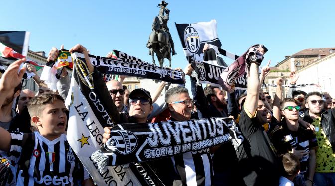 Suporter Juventus membentangkan shal merayakan kemenangan usai merebut gelar Serie A Italia di pusat kota Turin, Italia (25/4). Juventus berhak meraih gelar Scudetto mereka yang ke-34. (REUTERS/Giorgio Perottino)